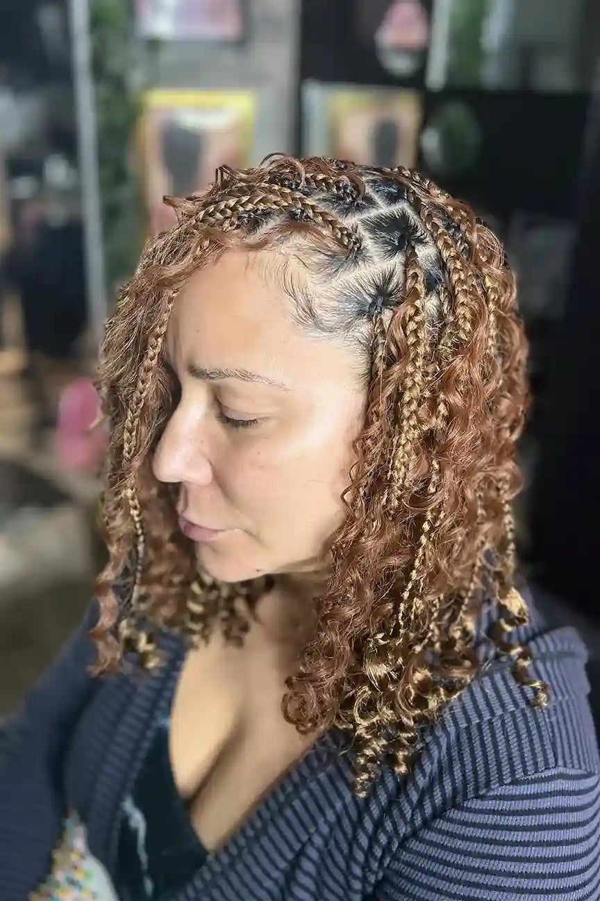 Woman with braided hair looking down, blurred background