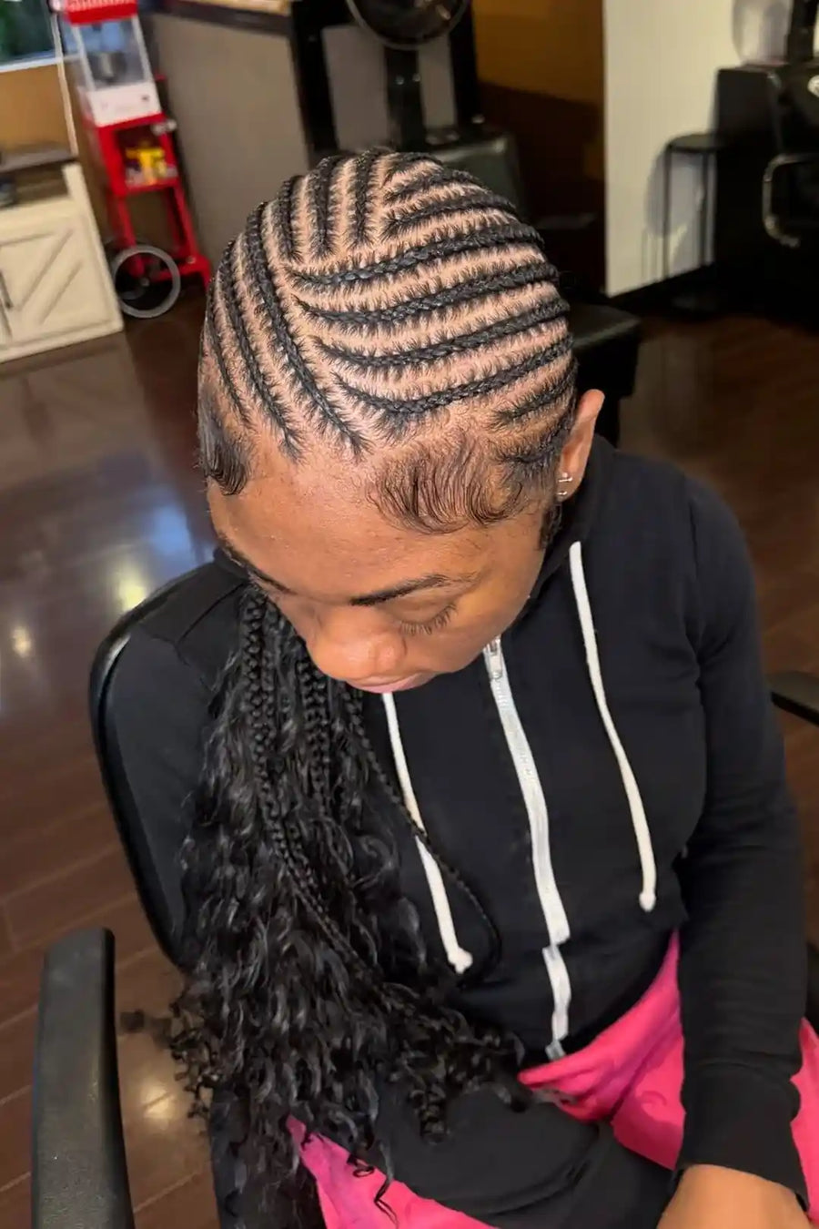 Person with braided hair sitting in a chair indoors