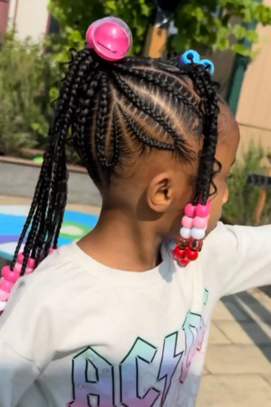 Child with braided hair wearing colorful beads outdoors