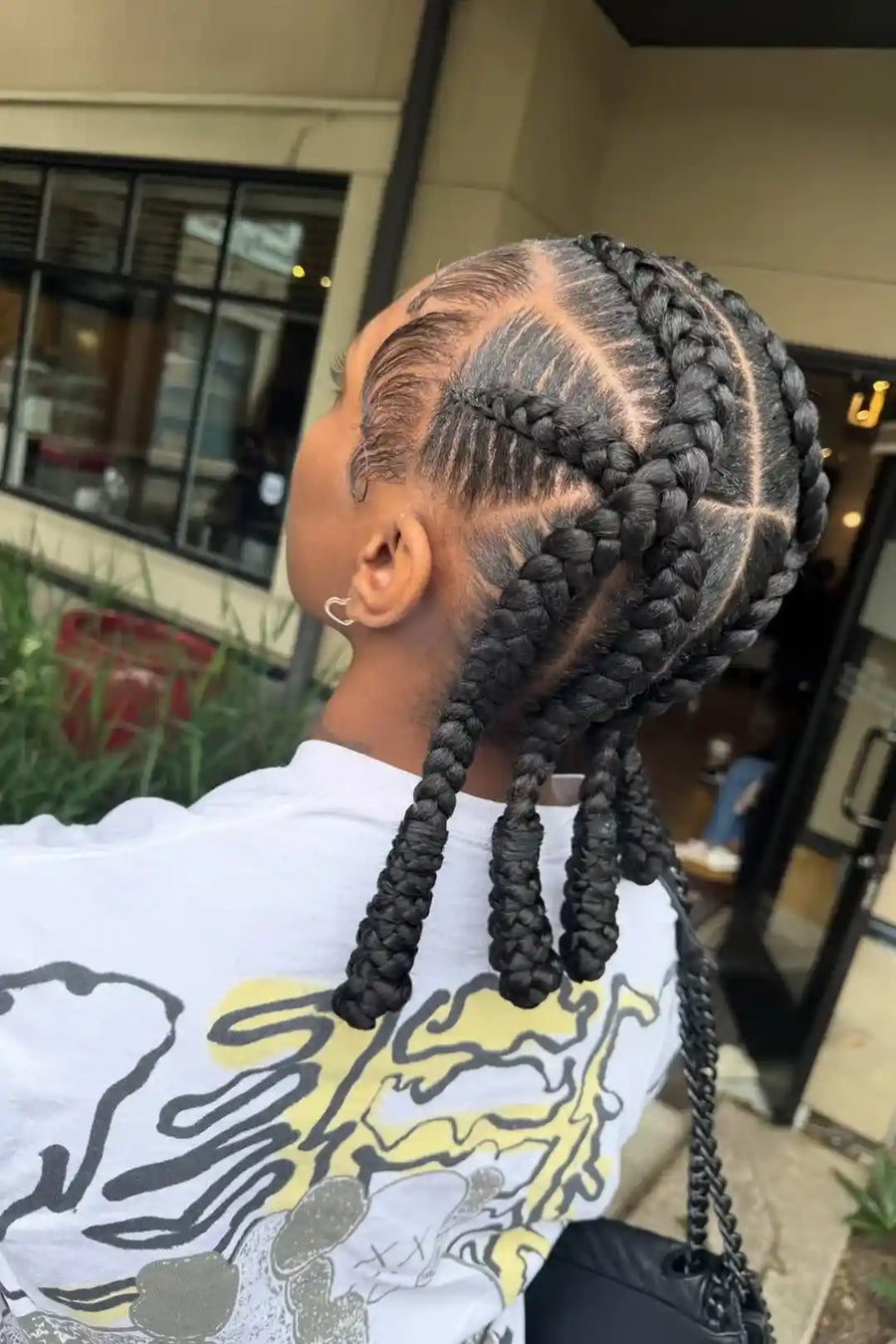 Person with braided hair wearing a white shirt with a graphic design.